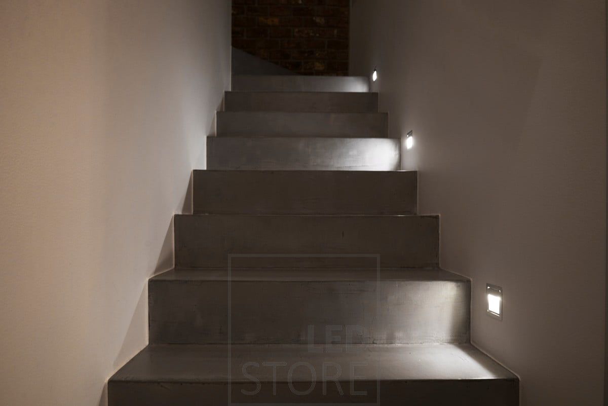 At every third step, a wall-mounted light fixture illuminates the steps.